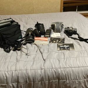 Canon AE-1 film camera with accessories, additional lenses, flash, and manuals
